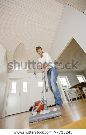 Woman cleaning the house with the Vacuum Cleaner
