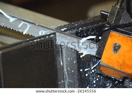 Frozen action shot of bandsaw blade showing teeth and coolant