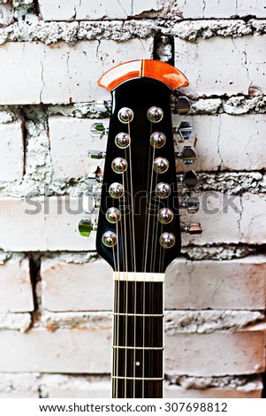 the electro-acoustic guitar leans on a brick wall