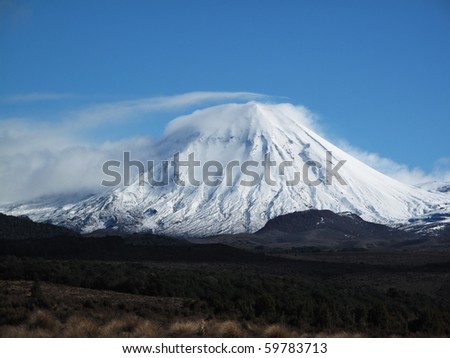 Mount Ngauruhoe covered in snow wearing a veil of cloud with tuntra in the foreground