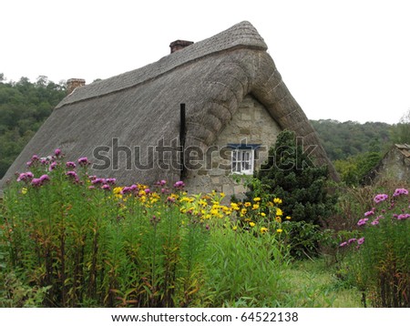 Traditional decorative thatched cottage buried in a cottage garden