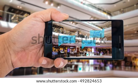 Augmented reality application for retail business concept. Hand holding smart phone with A/R application on screen to finding shop in department store. Represent A/R application in business.