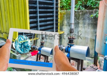 Industry 4.0 and Augmented reality for industry concept. Hand holding tablet with A/R maintenance application to identify machine part repair with refrigeration container in factory background.