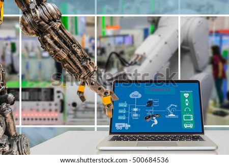 Cyber - Physical production or Industry 4.0 benefit concept. Robot arm is pressing laptop computer with Industry 4.0 diagram on screen against the smart manufacturing workshop.