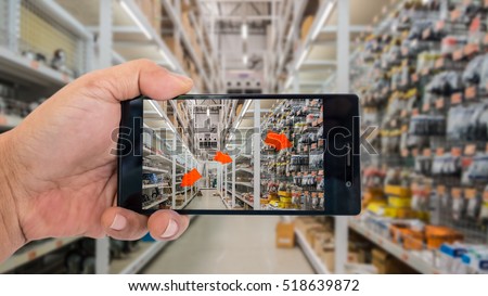Augmented reality application for retail business concept. Hand holding smart phone with A/R application on screen to finding interested product in construction depot.