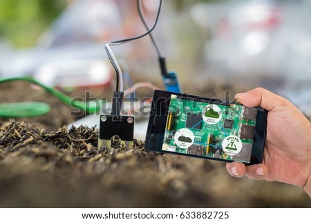 Agricultural technology concept. Smart farmer holding smart phone with agritech icons and messages on screen with soil sensor to manage water, soil quality and monitor weather.