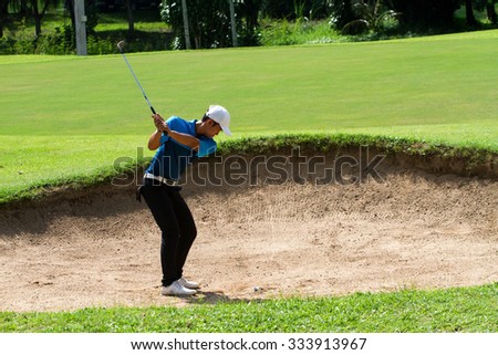 young man golf player hit ball in sandpit under sunlight in golf practice