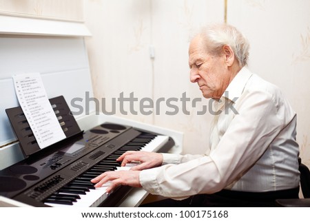 grey-haired senior man playing piano