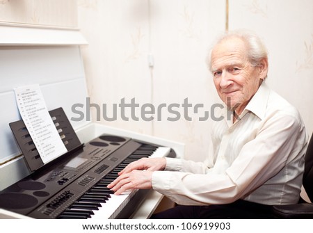 smiling pleased senior man playing piano