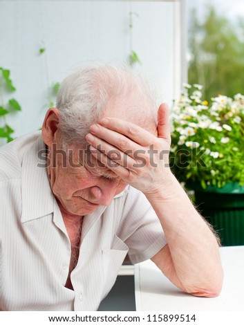 face portrait of an old senior man, he has a headache, his hand on his forehead