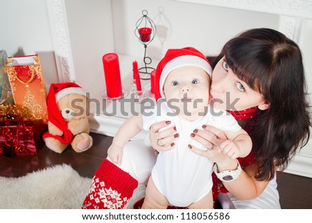 young mother kissing her little son, the boy is in Santa\'s cap