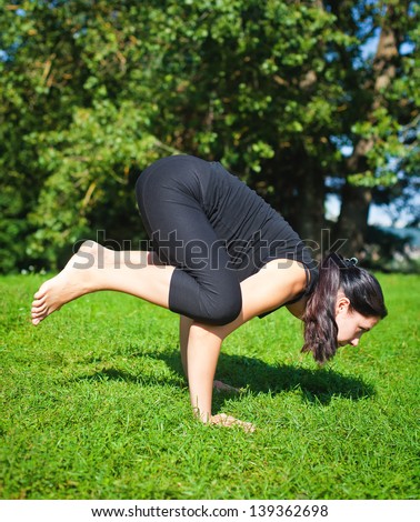 woman in black making yoga balancing asana - crow pose