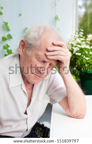 portrait of an old senior man, he has a headache, his hand on his forehead