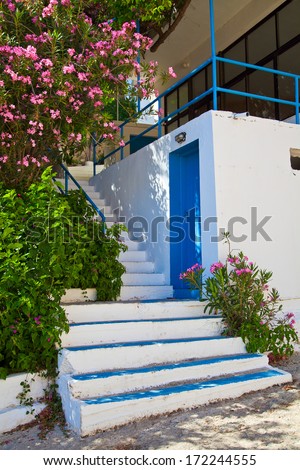 typical footsteps and blue entrance door on white-washed house, Greece