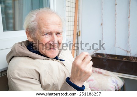 smiling old man holding a cigarette, its a bad habit, but he is enjoying it
