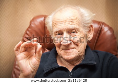 old smiling man holding a tablet, he is going to take some medicine