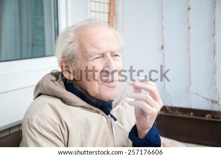 thoughtful old man with a cigarette, he is exhaling smoke