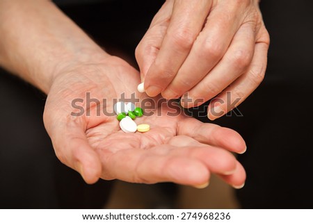 close-up old man\'s hands with pills, he is taking one of them