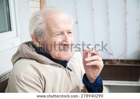 thoughtful old man smoking a cigarette and musing upon a distant scene
