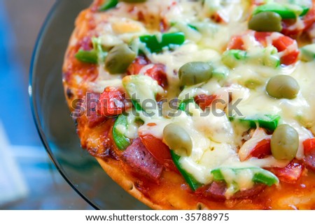 closeup pizza with salami, tomatoes, green pepper, olives and cheese