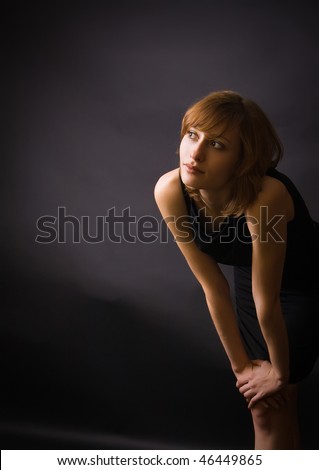 portrait of young woman in a studio, with black background, she is looking somewhere