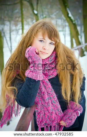 portrait of a young woman with long hair, she is in a winter pink scarf and gloves