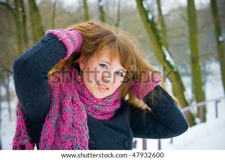 portrait of a beautiful woman in winter pink scarf and gloves, she is raising her hair up
