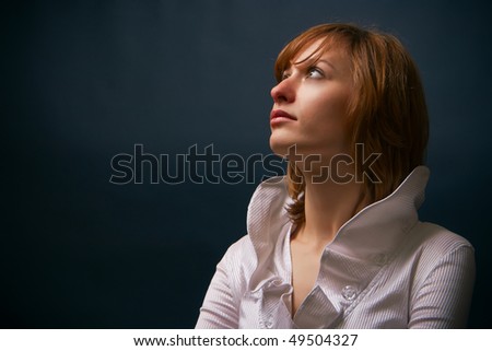 portrait of a young woman in white blouse in a studio, she is looking up