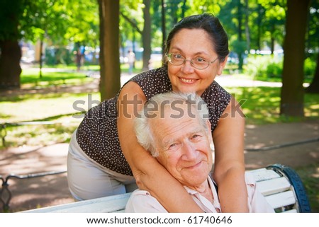 smiling mature couple enjoying fresh air in a park, they are different age, but they love each other