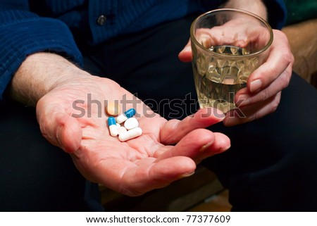 close-up old man\'s hands with pills and glass of water, he is going to take some medicine