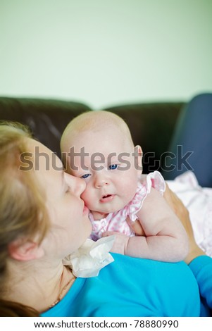 young woman lying on her back on a couch kissing her little baby