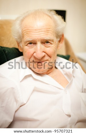face portrait of a smiling senior man sitting in an armchair