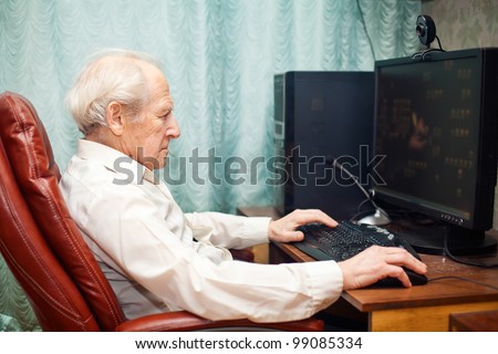 old man sitting in a chair and working with computer