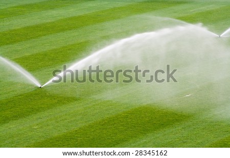 Water jets sprinkling a soccer stadium field.