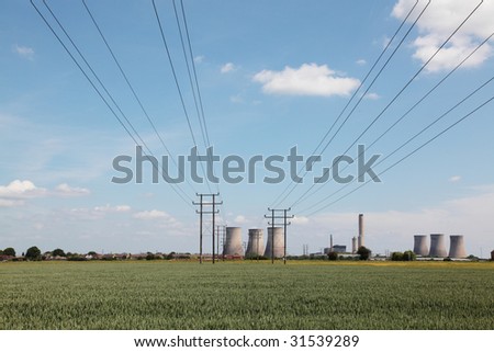 Electrical cables leading away from the camera to a power plant in the background