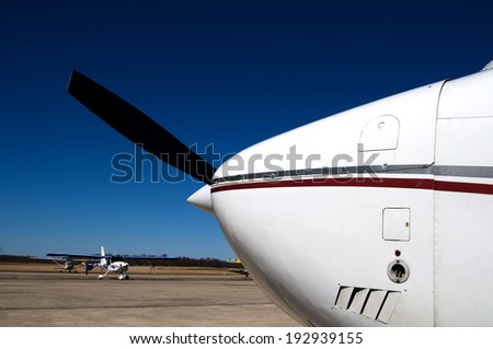 Close-up of the nose-cone and propeller of a single-engine aircraft on a runway