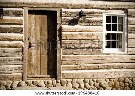 A primitive log cabin set atop a stone foundation.