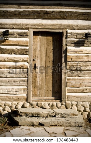 A log cabin with two lanterns of each side of the door.