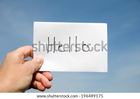 A hand holding a piece of paper that has hello written on it.