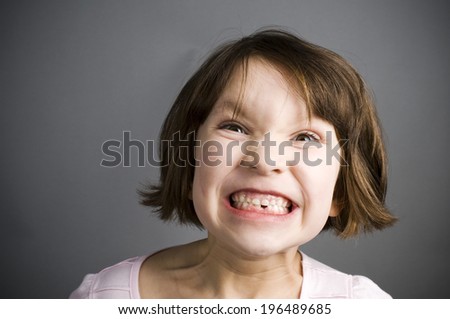 A little girl with a big grin showing off her missing tooth.