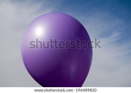 A purple balloon against a cloudy blue sky.