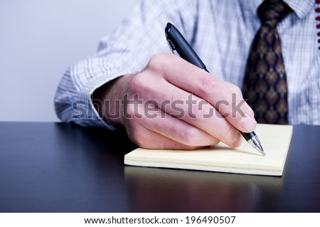 A man writing on a pad of paper.