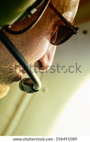 A man with stubble wearing sunglasses and a headset.