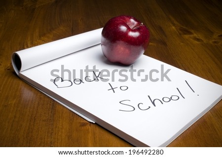 A note pad with the note Back to School with a red apple.