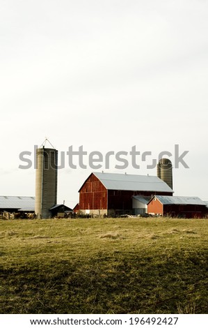 A farm with three buildings and two grain silos.