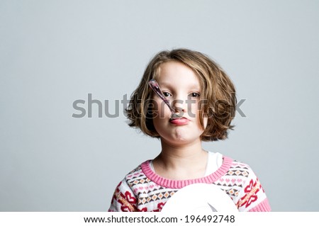 A young girl holding a spoon in her mouth.