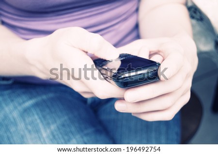 A person sitting down and holding a cell phone.