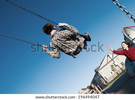 A child riding high on a swing on a clear day.