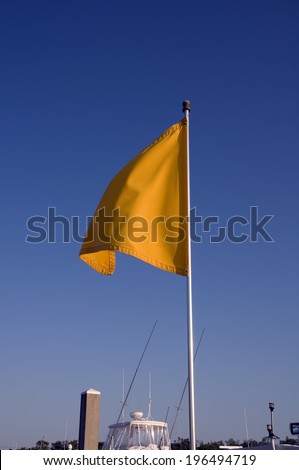 A flagpole holding an orange flag above a boat.