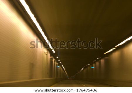 A lit up street tunnel at high speed.